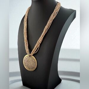 Tribal vintage gold tone 7 strand 16” beaded necklace with round pendant.